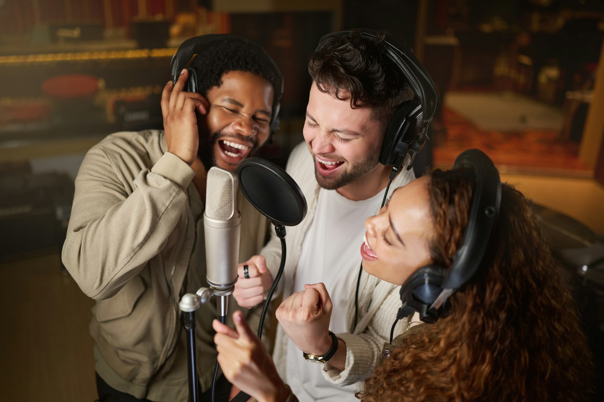 Music, streaming and diversity, band recording in studio singing into microphone with headphones an